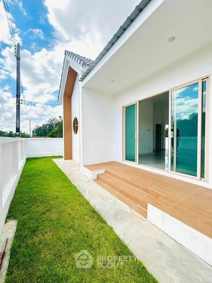 Modern white house with sliding glass doors and lush green lawn