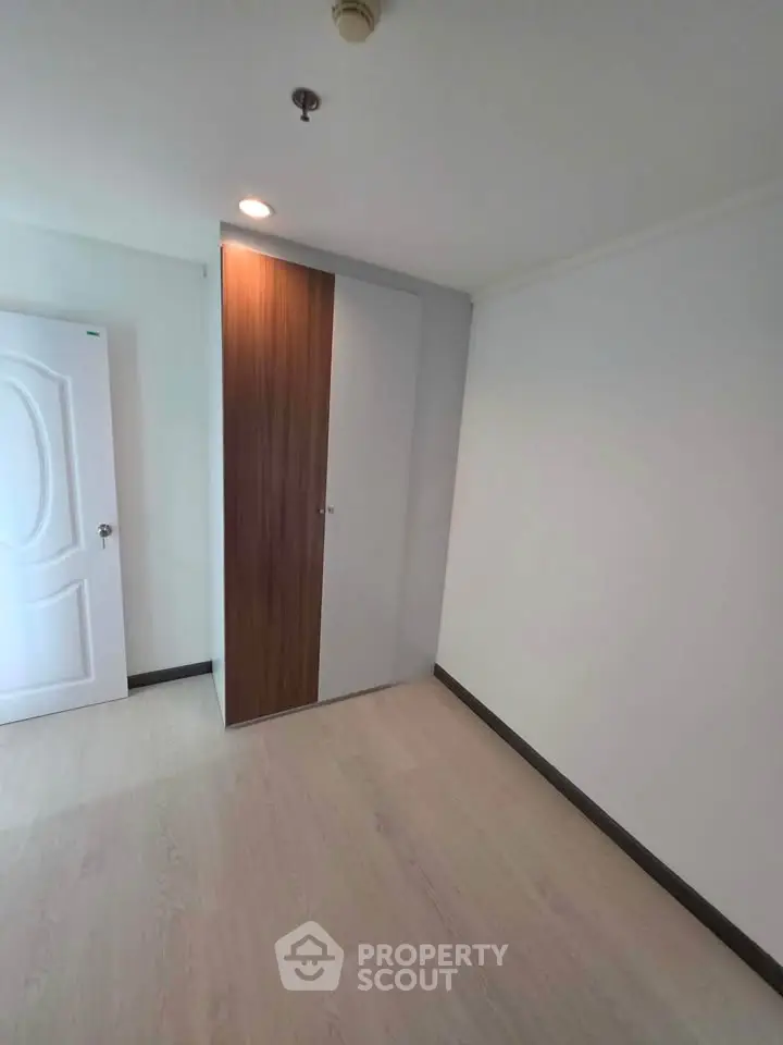 Spacious empty room with modern wooden closet and white walls, perfect for customization.