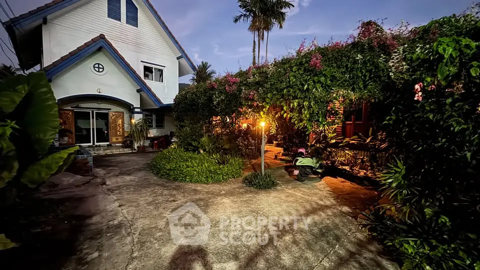 Charming house with lush garden and evening ambiance, perfect for tranquil living.
