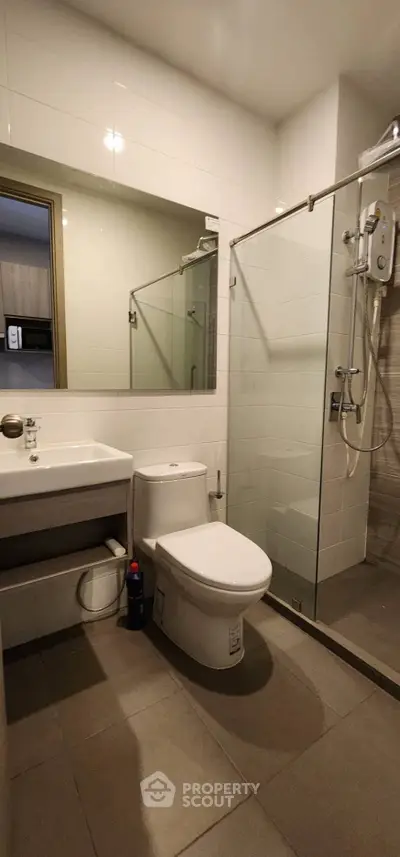 Modern bathroom with glass shower and sleek fixtures in contemporary apartment.