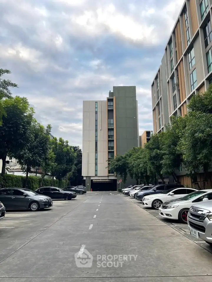 Modern apartment building with spacious parking area and lush greenery.