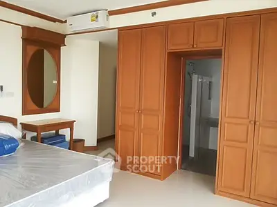 Spacious bedroom with wooden wardrobe and modern air conditioning unit.
