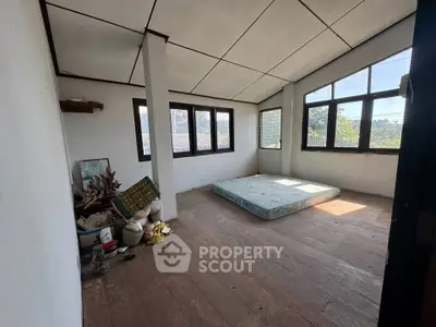 Spacious room with large windows and wooden flooring, ideal for renovation.