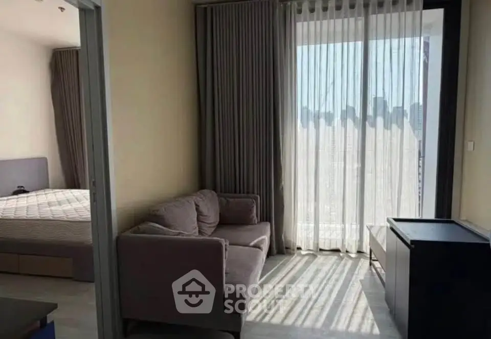 Modern apartment with cozy living area and bedroom, featuring large windows and elegant curtains.