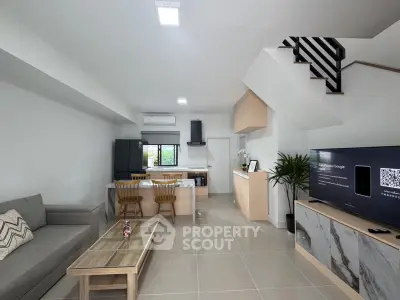 Modern open-plan living room with sleek kitchen and stylish staircase, perfect for contemporary living.