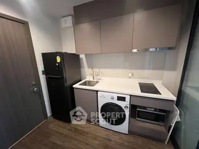 Modern kitchen with sleek appliances and compact design, featuring a washing machine and induction cooktop.