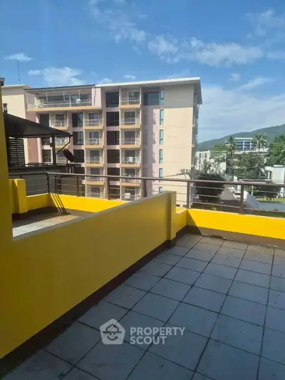 Spacious balcony with scenic view of modern apartment building and lush greenery.