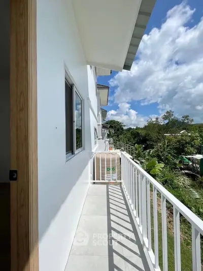 Spacious balcony with scenic view of lush greenery and clear blue sky, perfect for relaxation.