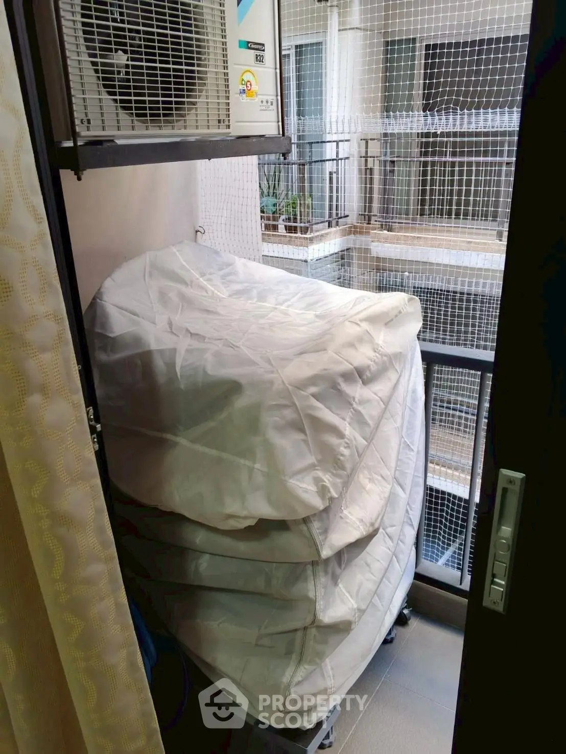 Compact balcony with stacked mattresses and air conditioning unit