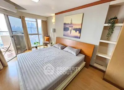 Spacious bedroom with balcony and city view, featuring modern decor and ample natural light.