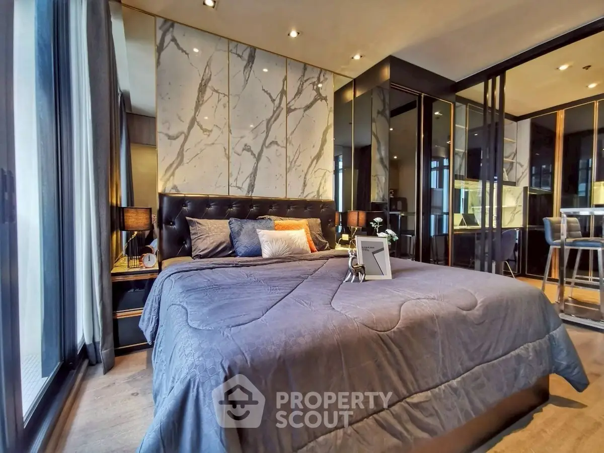 Luxurious modern bedroom with elegant marble accents and plush bedding in upscale apartment.