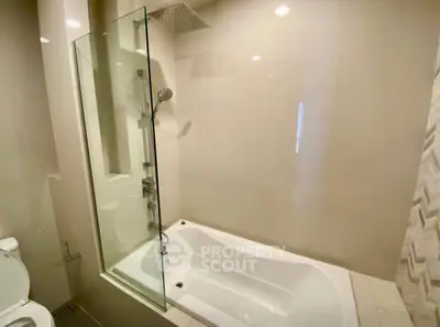 Modern bathroom with sleek bathtub and glass shower partition in a contemporary apartment.