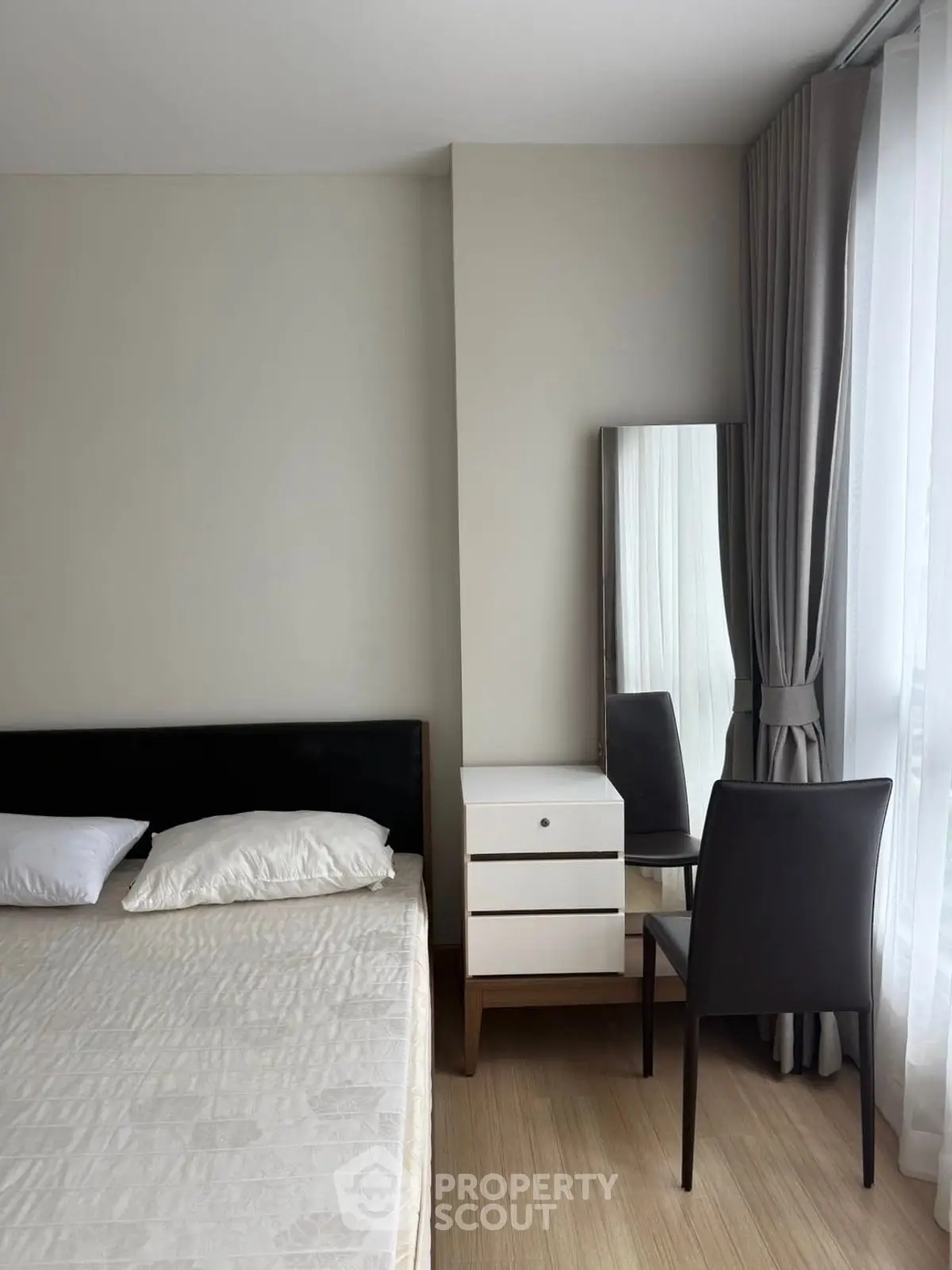 Modern bedroom with sleek furniture and natural light through large window.
