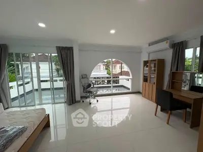 Spacious modern bedroom with large windows and balcony access, featuring sleek furniture and abundant natural light.