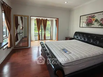 Spacious bedroom with elegant decor and large windows offering natural light.