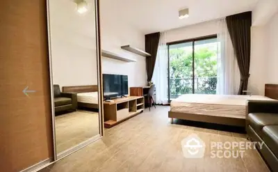 Spacious bedroom with modern design, large bed, and a cozy sitting area opening to a serene green view through floor-to-ceiling windows.