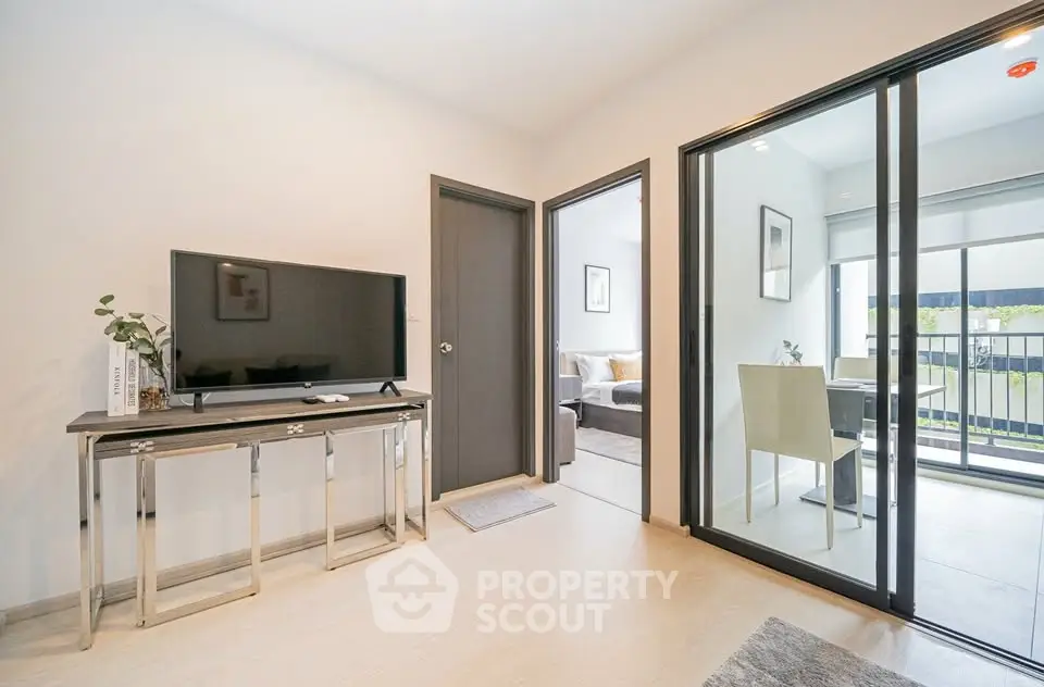Modern living room with sleek TV setup and sliding glass doors to balcony