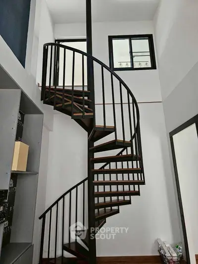 Modern spiral staircase in a stylish interior with high ceilings and sleek design.