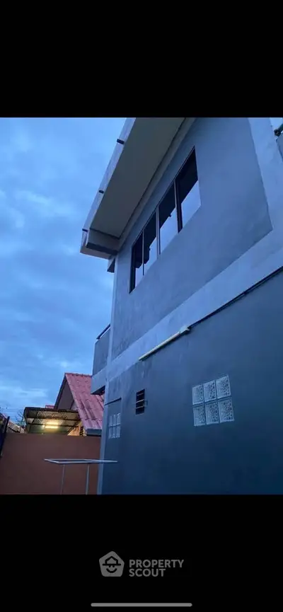 Modern two-story building exterior with sleek design and large windows at dusk.