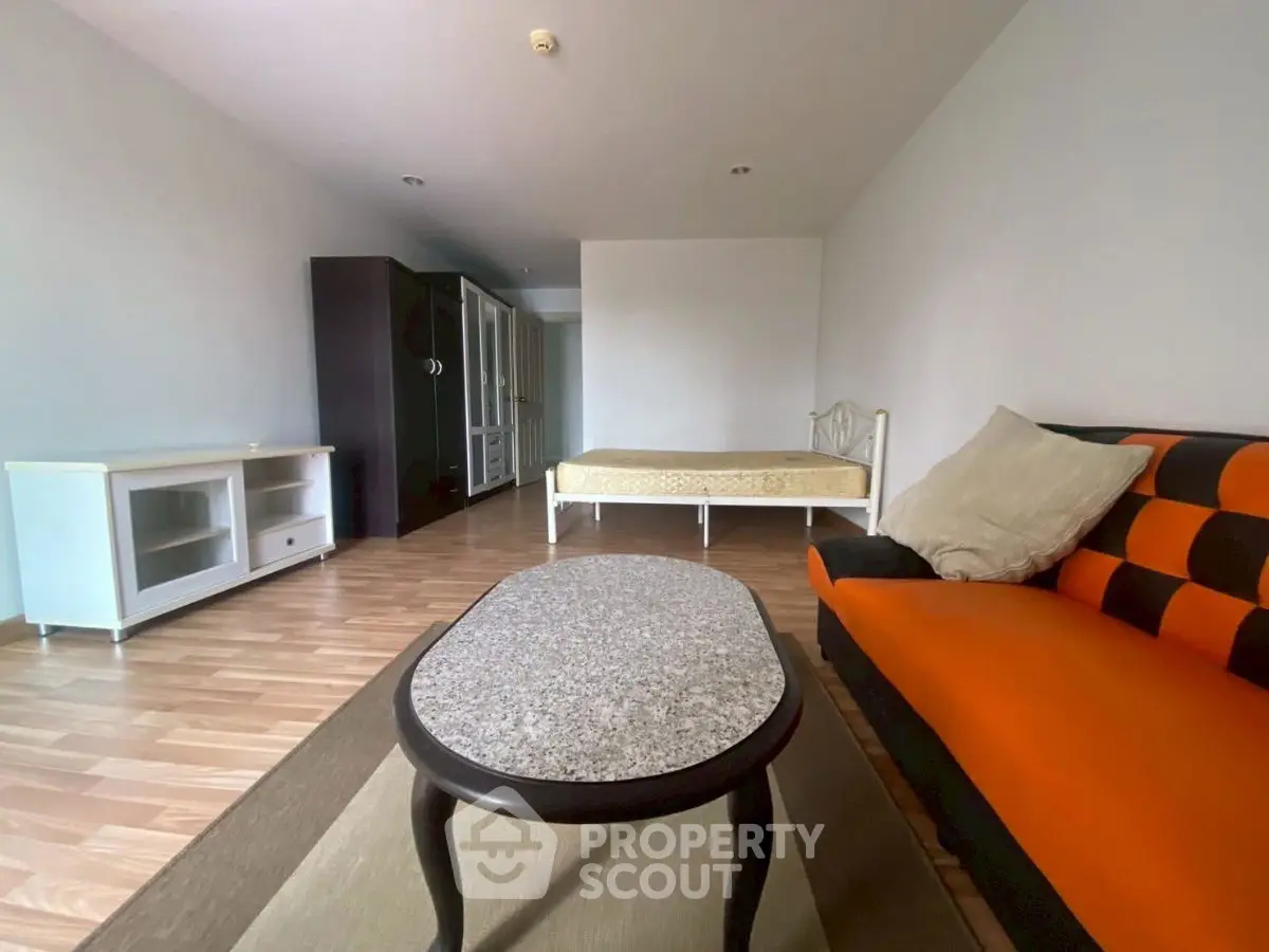 Spacious studio apartment with modern furnishings and wooden flooring.