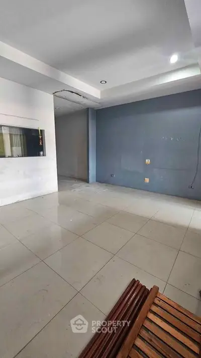 Spacious empty room with tiled flooring and modern recessed lighting, ideal for customization.