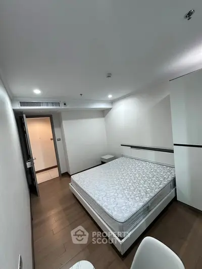 Modern minimalist bedroom with wooden flooring and sleek furniture design.