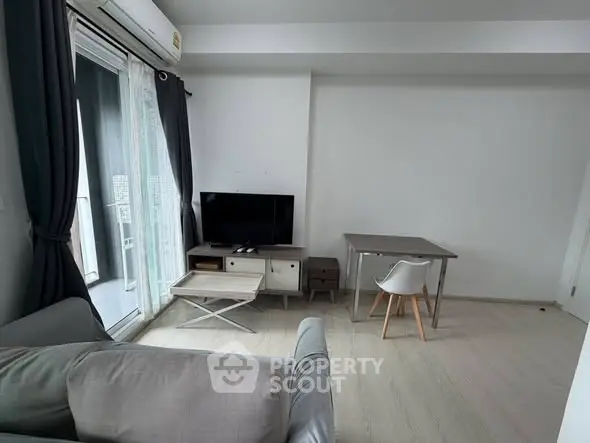 Modern living room with balcony access, featuring sleek furniture and natural light.