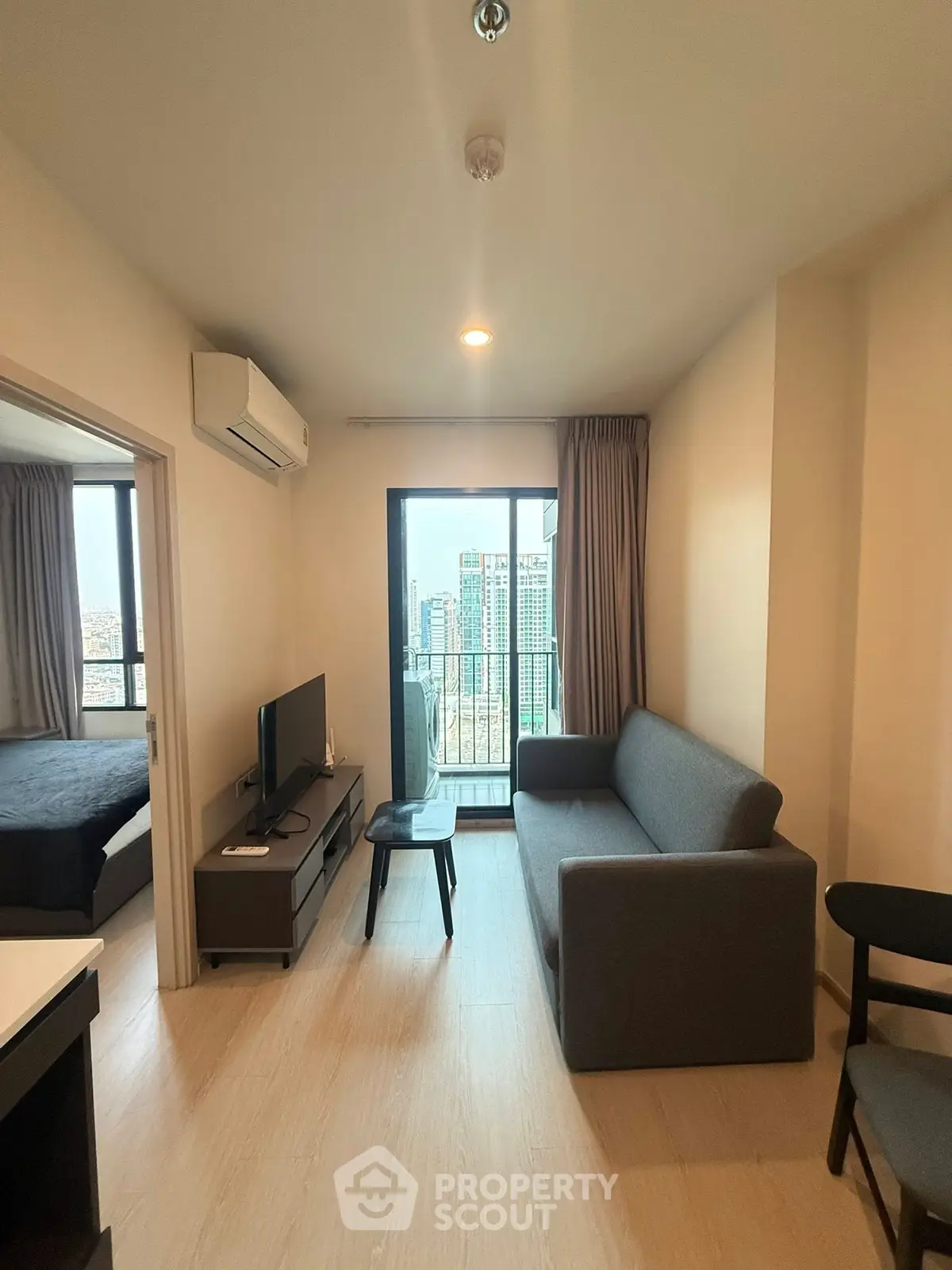 Modern living room with city view, featuring a cozy sofa and sleek TV setup, perfect for urban living.