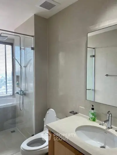 Modern bathroom with glass shower and sleek fixtures in bright natural light.