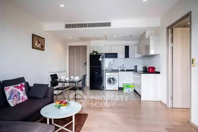 Modern open-plan living room and kitchen with sleek appliances and stylish decor.