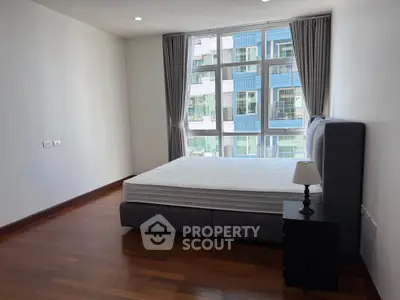 Spacious bedroom with large windows and modern furnishings in a high-rise apartment.