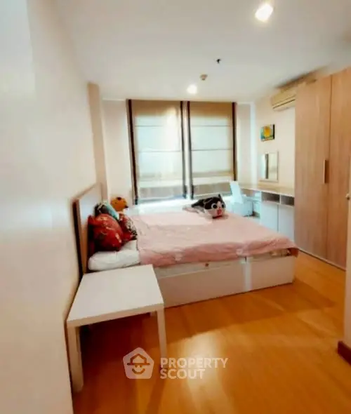 Cozy bedroom with wooden flooring and large windows for natural light