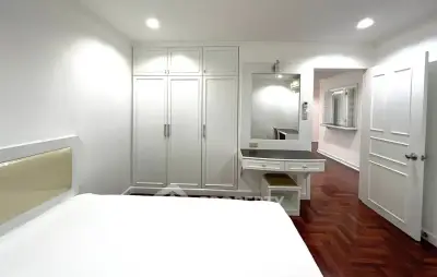Spacious bedroom with elegant white wardrobe and vanity in modern apartment