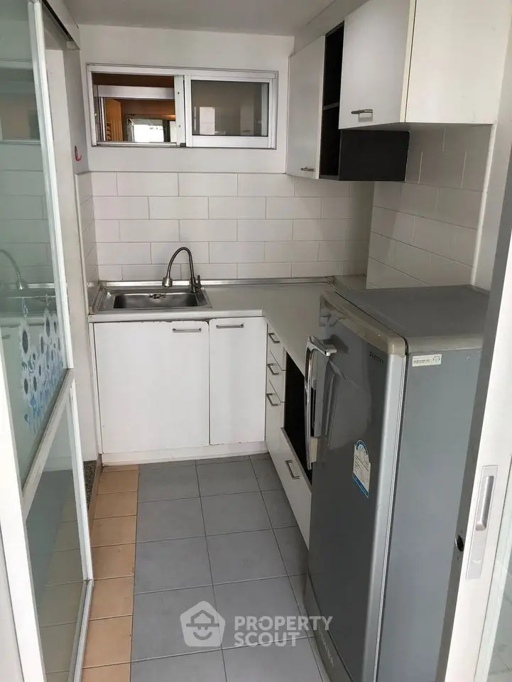 Compact kitchen with modern appliances and sleek cabinetry in a cozy apartment.