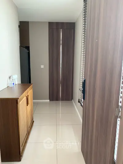 Modern hallway with sleek wooden cabinetry and glossy tiled flooring