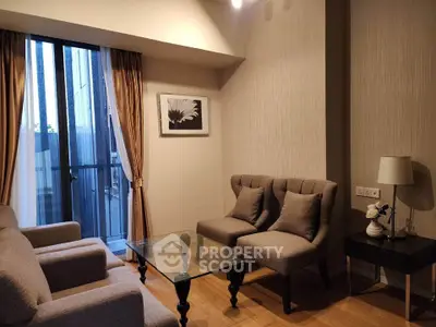 Cozy living room with elegant furniture and glass coffee table near balcony.