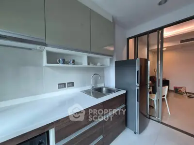 Modern kitchen with sleek cabinets and stainless steel fridge in stylish apartment.