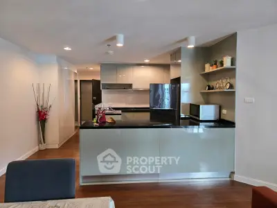 Modern kitchen with sleek cabinetry and appliances in open layout apartment