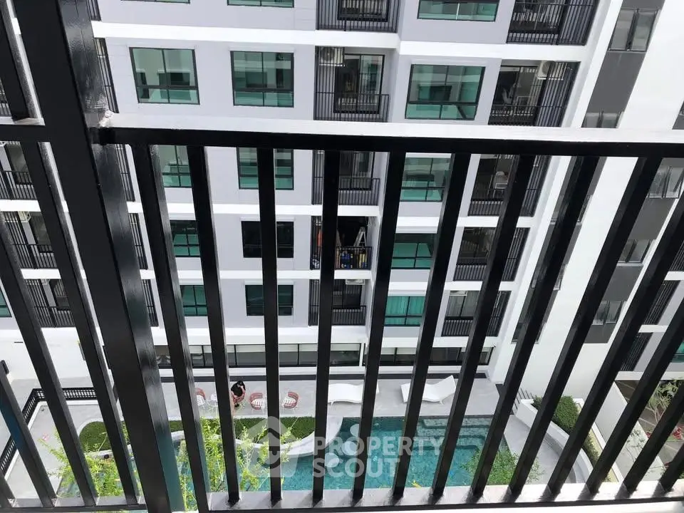Modern apartment building with pool view from balcony, showcasing urban living.