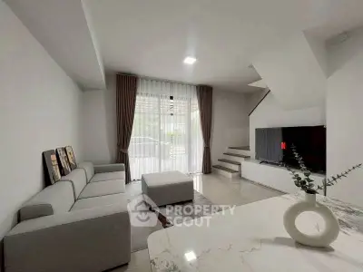Modern living room with sleek gray sofa, large TV, and elegant decor in a stylish open-plan home.