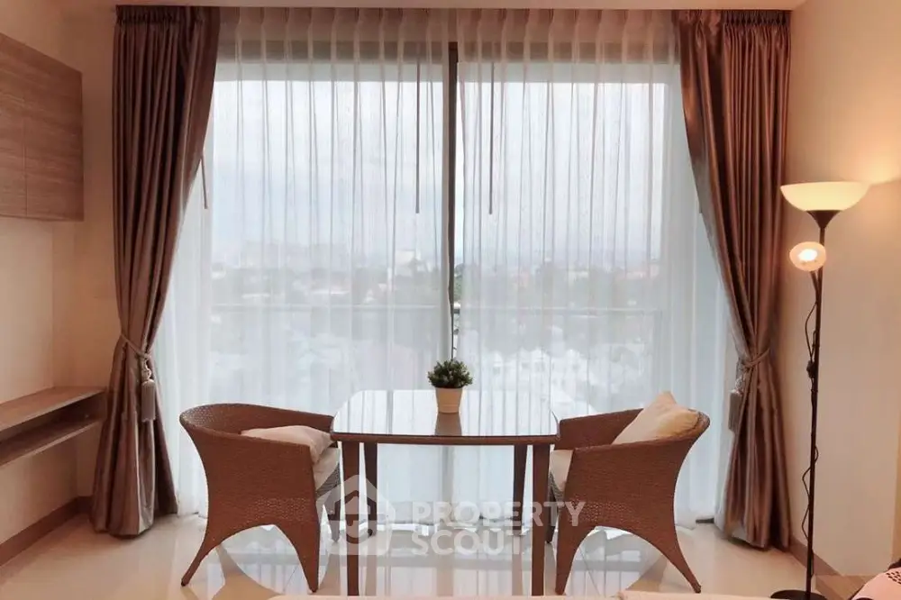 Elegant living room with large window and cozy seating area, perfect for relaxation.