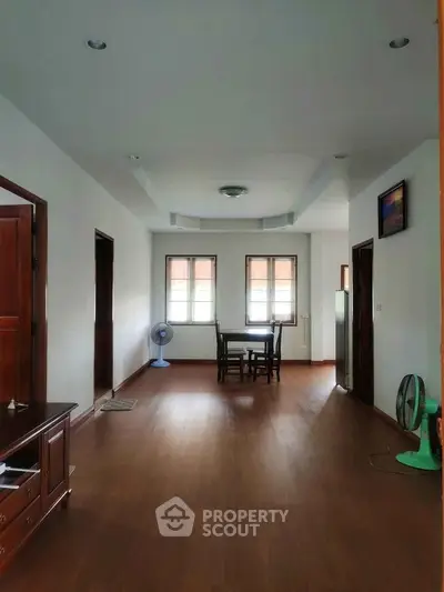 Spacious living area with wooden flooring and natural light