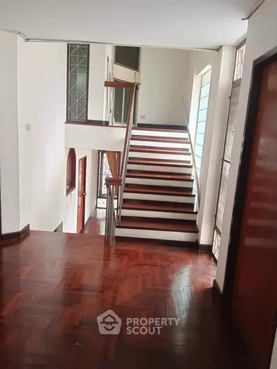 Elegant wooden staircase in a modern home with polished floors and natural light.