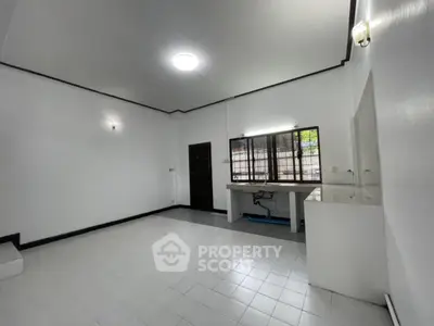 Spacious minimalist room with white tiles and large window, ideal for versatile use.