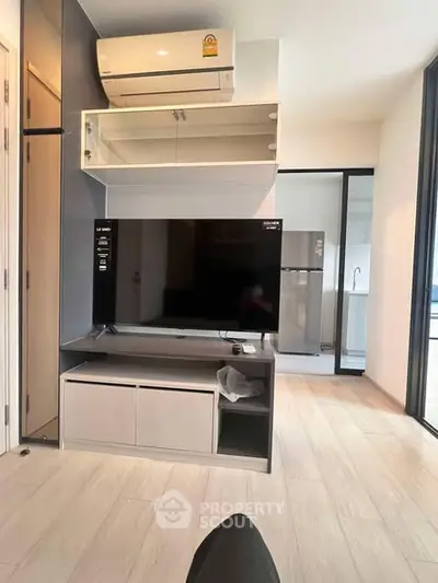 Modern living room with TV, air conditioner, and sleek storage units.