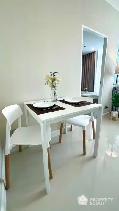 Modern dining nook with white table and chairs in a cozy apartment setting.