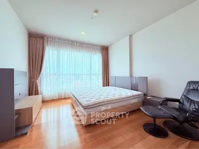 Spacious bedroom with large window and modern furnishings in a luxury apartment.