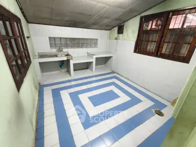 Spacious kitchen with unique blue and white tiled floor, featuring large windows for natural light.