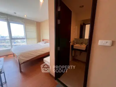 Modern bedroom with ensuite bathroom and city view, featuring wooden flooring and large windows.