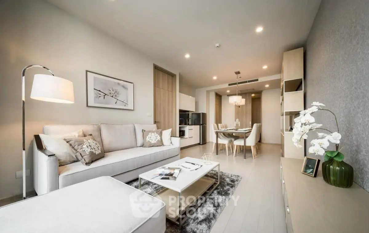 Modern living room with elegant decor and open dining area, featuring neutral tones and stylish furnishings.